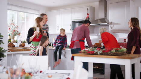 Un-Hombre-Saca-El-Pavo-Del-Horno-Mientras-Una-Familia-Multigeneracional-Se-Sienta-Alrededor-De-La-Mesa-Para-Una-Comida-Navideña-En-Casa-Juntos