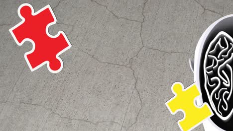 animation of green, yellow and red puzzle pieces falling over model of human head on grey background