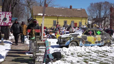 black men walk through a neighborhood in detroit filled with abandoned items and art objects 1