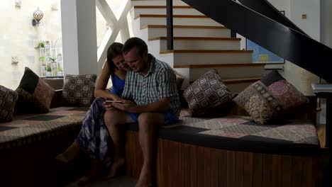 hombre y mujer viendo un video gracioso en el teléfono inteligente sentados en el sofá en casa
