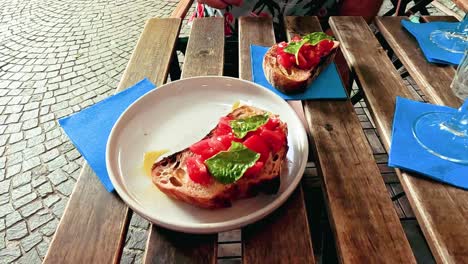 hand reaching for tomato basil bruschetta on table