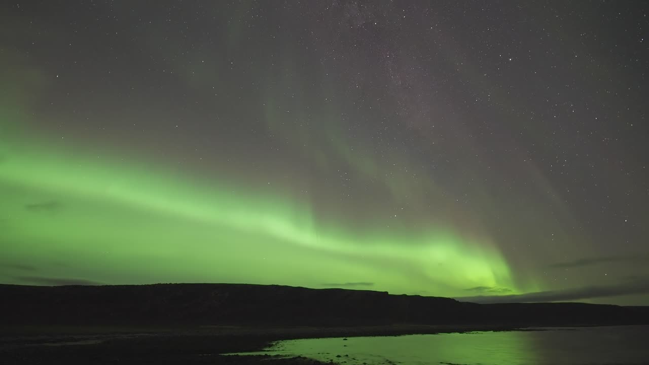 la fascinante aurora boreal sobre un tranquilo fiordo en una oscura noche de invierno - un video de lapso de tiempo
