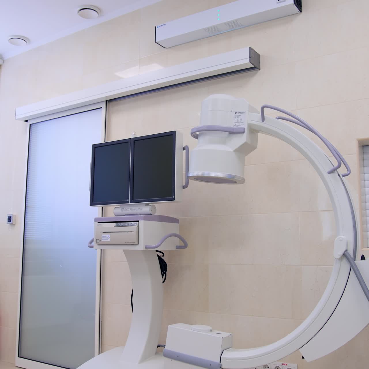 Macchina per fluoroscopia ad arco a C in una sala operatoria moderna. Tavolo operatorio con sistema di ventilazione polmonare nelle vicinanze