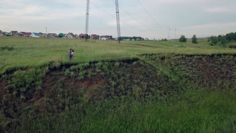 bird-eye-flight-young-couple-hugs-on-green-meadow-edge