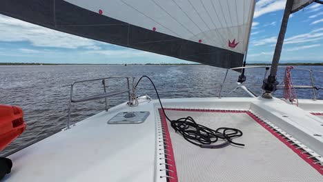 looking out from the port deck of a large catermeran as it sails peacefully across a bay