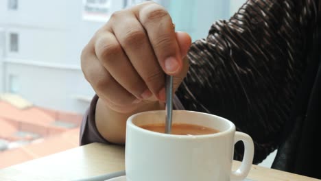 woman stirring a cup of tea in a cafe