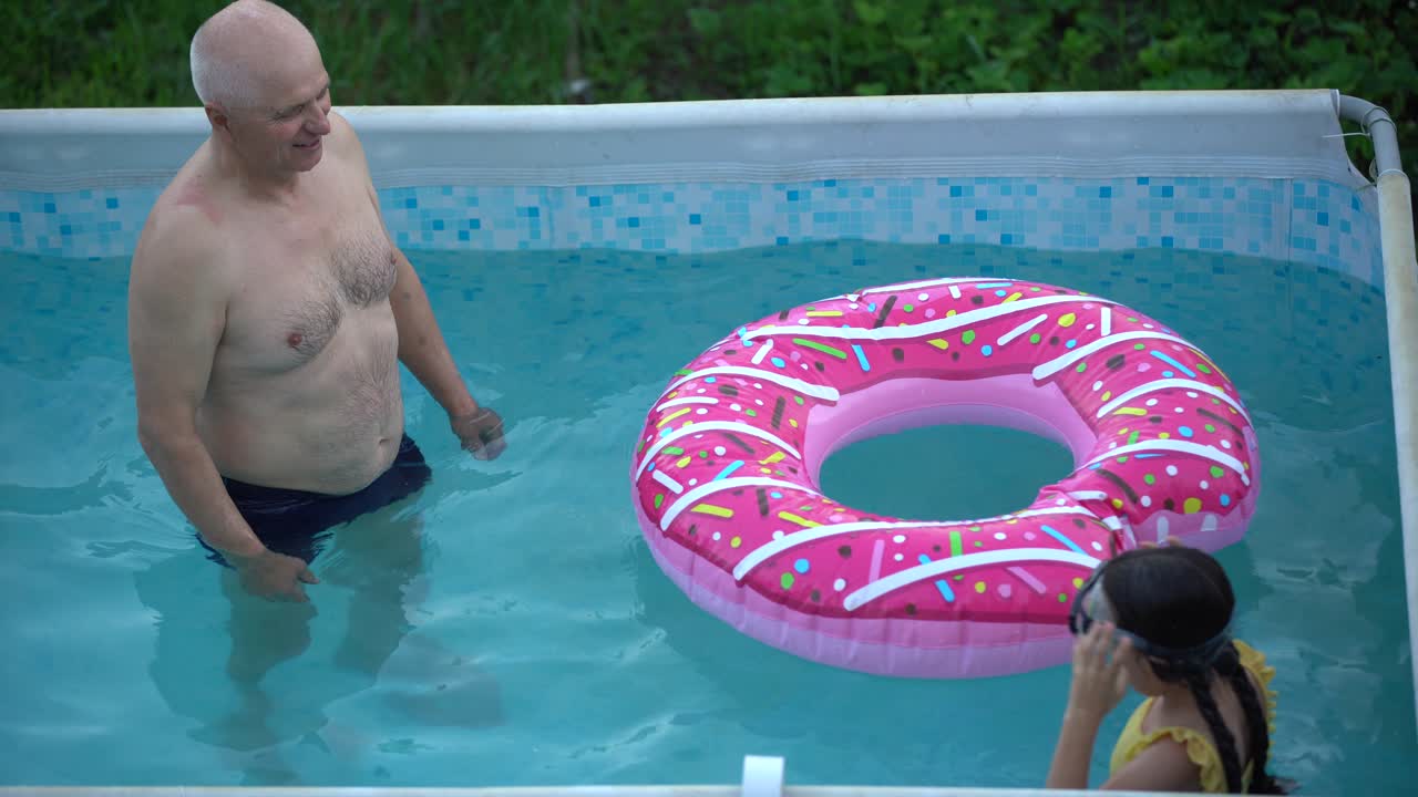 abuelo y nieta nadando en la piscina
