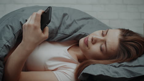 침대에서 스마트폰을 사용하는 여자
