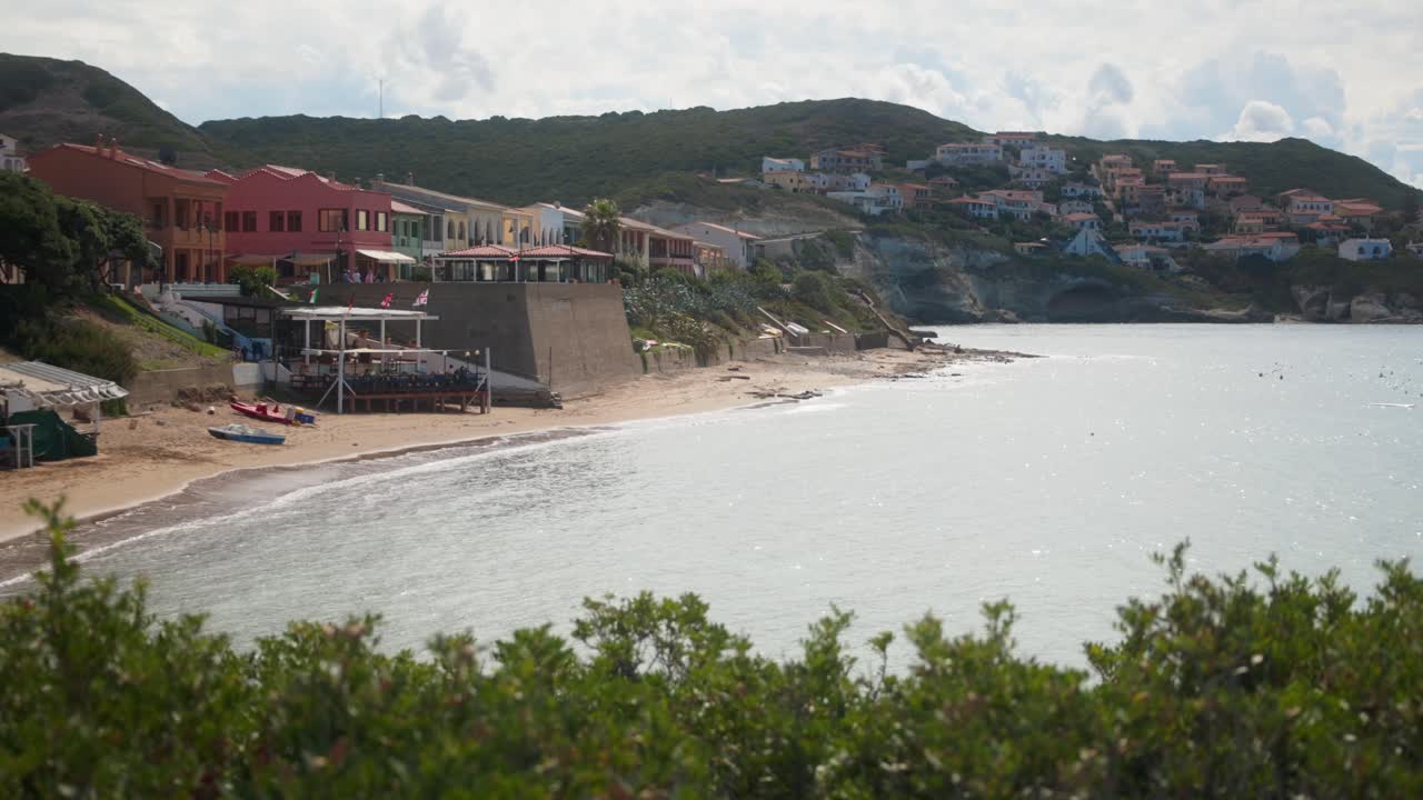 Charming beach bar elevated on the beachfront, offering stunning ocean views and a picturesque backdrop of a charming house perched on the hill.