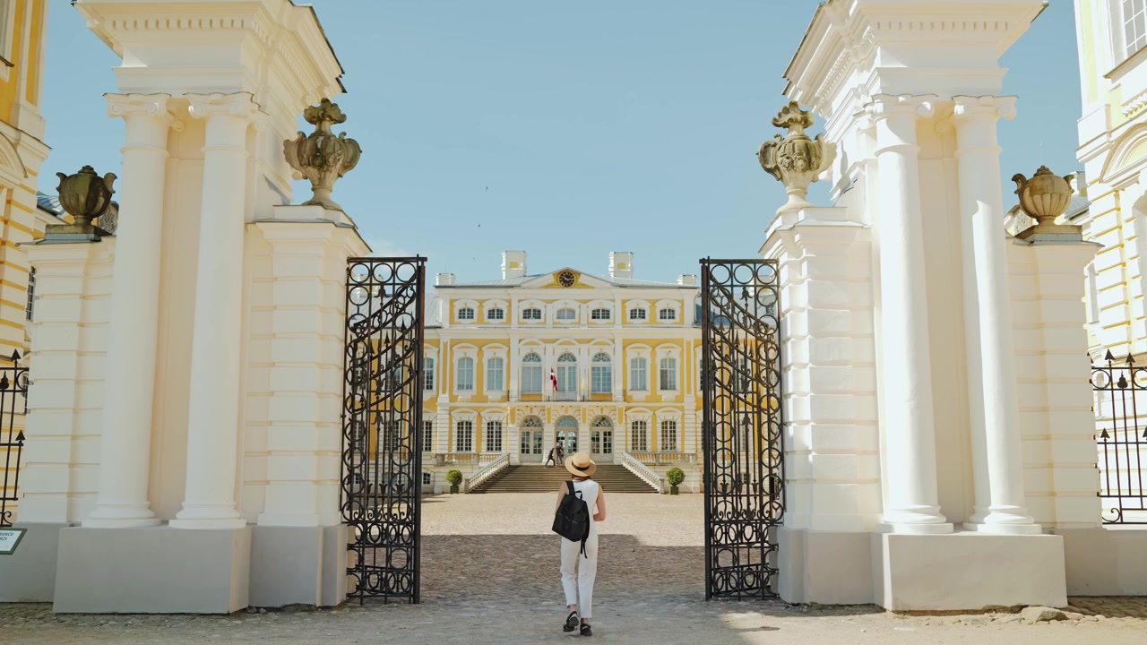 Mujer caminando hacia el patio del histórico Palacio de Rundale en un día soleado