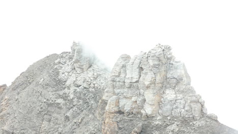 revelación aérea de una gran roca en la cima de la montaña cubierta de niebla espesa