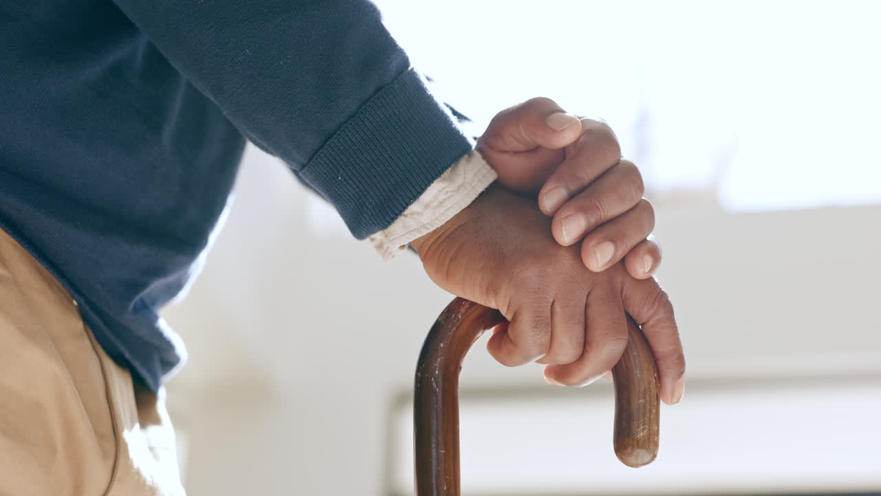 Cane, hands and elderly man in home living room