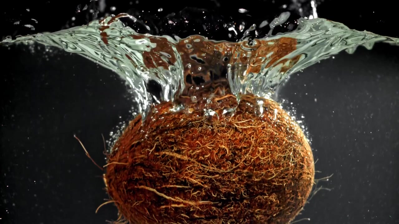 Whole Coconut Falling into Water with Splashes in Slow Motion