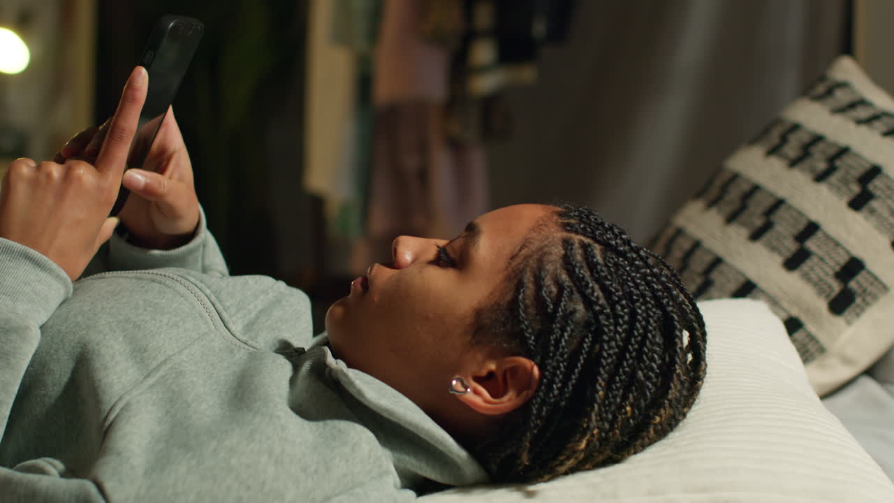 Teenager using smartphone or tablet lying on a bed at night