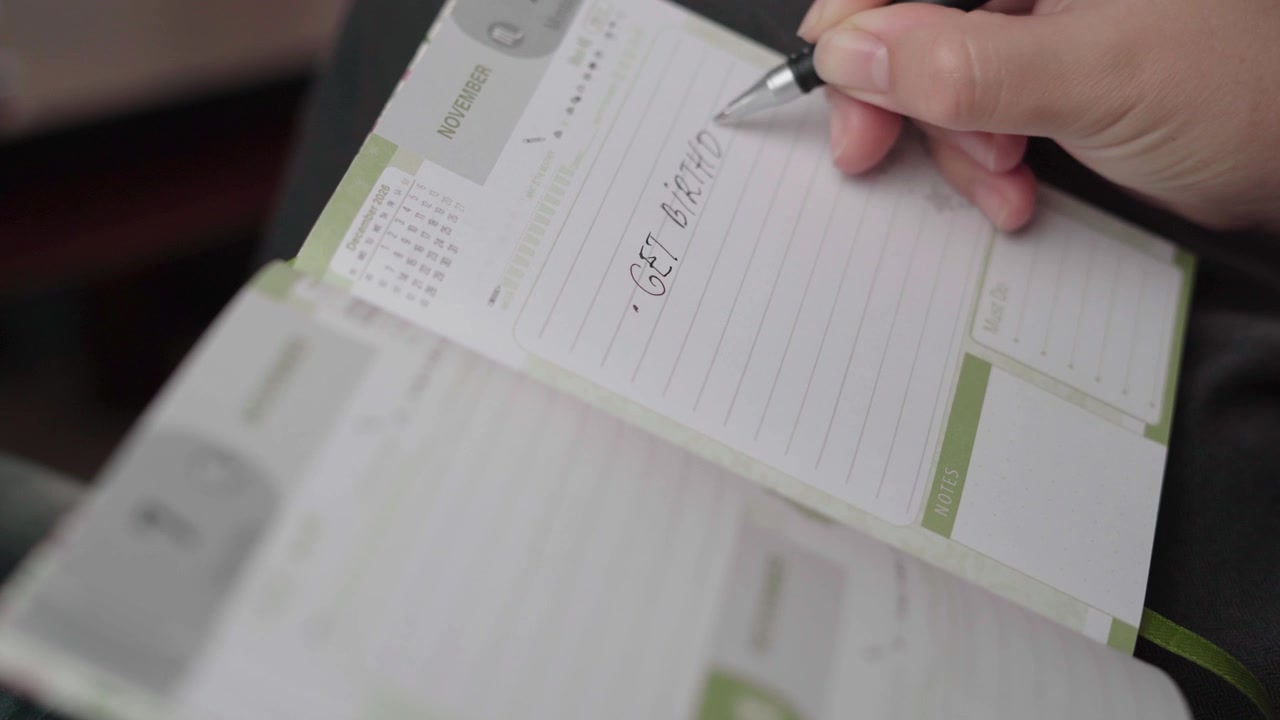 Calm indoor scene as a pen writes a birthday gift shopping task on a lined November diary page.