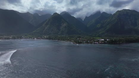 teahupoo ola tahiti polinesia francesa drone aéreo mañana soleada nublada picos del valle de la montaña lugar de las olimpíadas de verano de parís passe havae canal arrecife de coral punto faremahora surfista avance hacia arriba