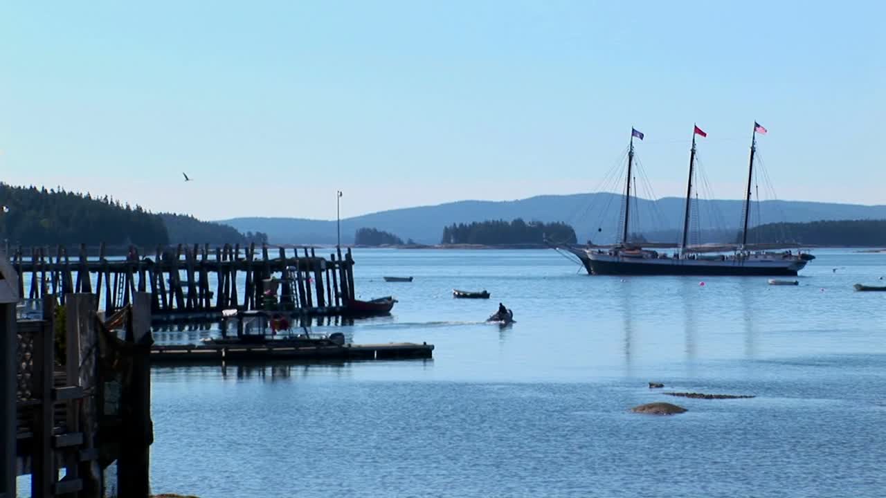 un velero está anclado cerca de un muelle de madera en alta mar un pueblo de langostas en stonington maine