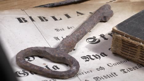 ancient key and bible with worn pages rest on a table