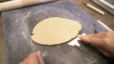 person shaping clay using tools