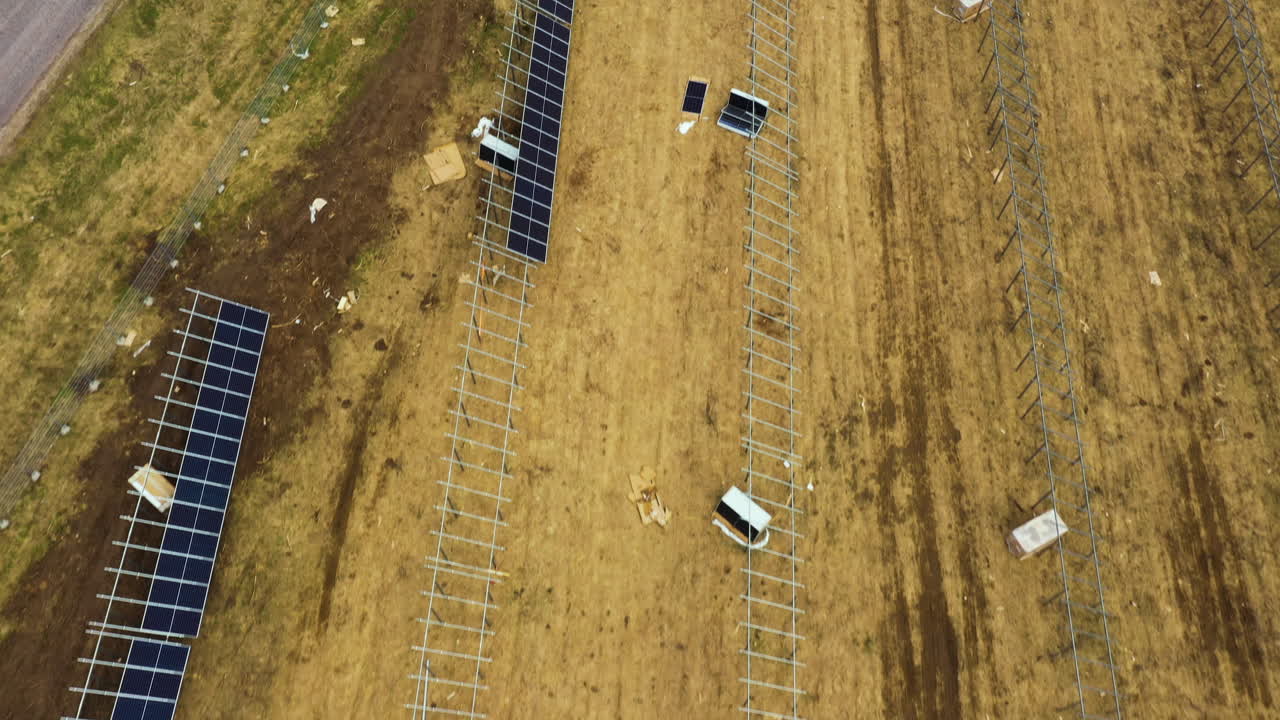 Luftfoto ovenfra af konstruktionen af en stor solcellepark med paneler og enheder på landet.