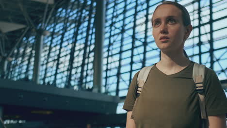 Woman-traveler-with-a-backpack-at-the-airport-looking-at-the-scoreboard-departures-looking-for-your-flight