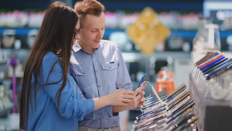 the couple chooses a mobile phone in an electronic store. showcase with smartphones