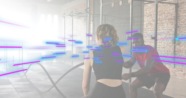 Fitness trainee gripping battle ropes and generating alternating waves while coach correcting form