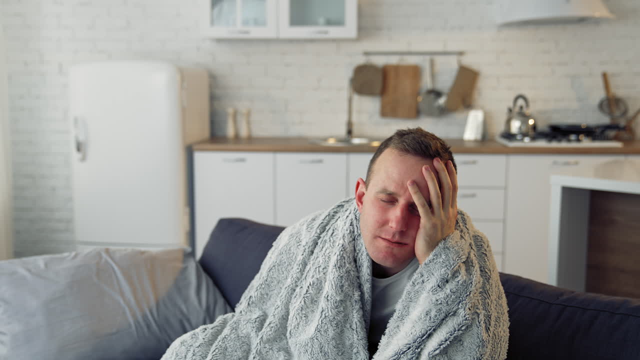 Sick young man suffering from flu at home. Pandemic. Quarantine concept.