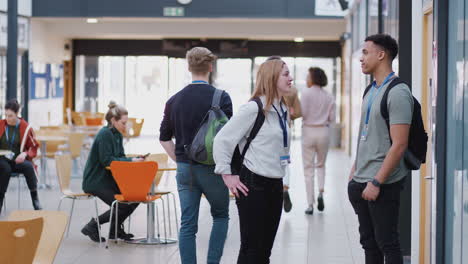 College Student Couple Meeting And Talking In Busy Communal Campus Building