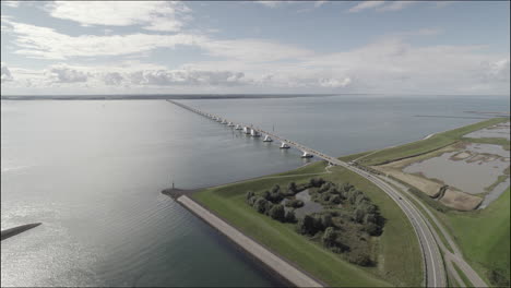 wide drone shot of the zealand bridge in the netherlands on a cloudy but bright day with cars driving over it log