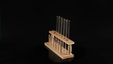 soporte de tubo de ensayo de madera giratorio sobre fondo negro