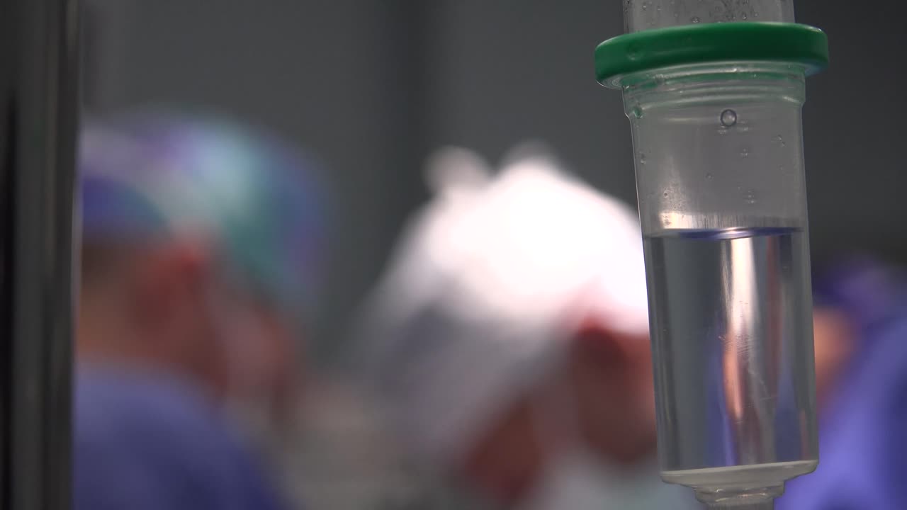 Surgery Medical drop counter on the blurry background of the doctors in the operating room.