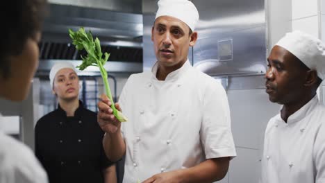 diverse group of chefs standing around a table listening to instructions