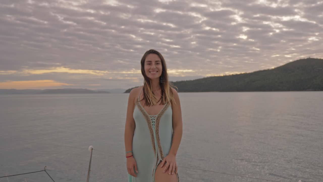 백그라운드에서 일몰 하늘과 바다와 함께 카메라에 미소 예쁜 여자