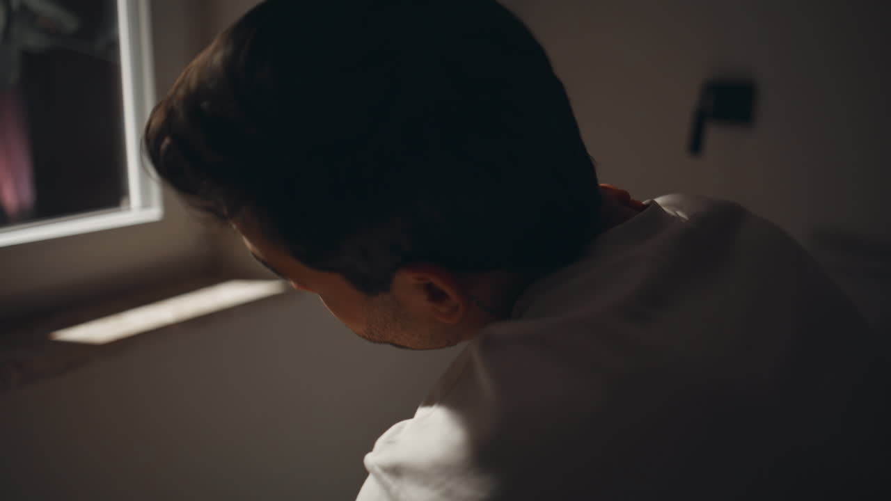 Sleepless man looking window with pensive mood closeup. Tired guy sitting bed