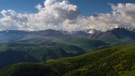 mountain range with snowy peaks and lush green hills