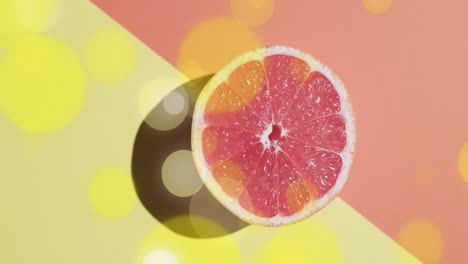 composition of halved grapefruit and yellow spots on yellow and red background