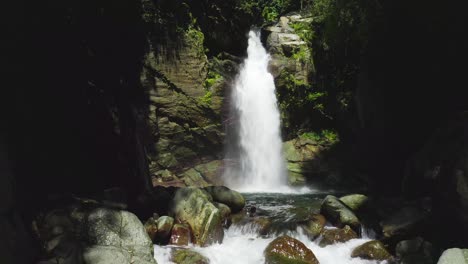 peaceful and tranquil summer scenery of waterfall cascading down rocky mountain facade in forest, handheld pan