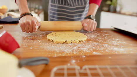 Biracial-man-wearing-christmas-hat,-making-christmas-cookies-in-kitchen-at-home,-slow-motion