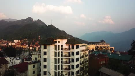 Ascending-pedestal-shot-of-an-apartment-building-reveals-a-town-and-large-antenna-in-a-mountainous-region-of-Asia