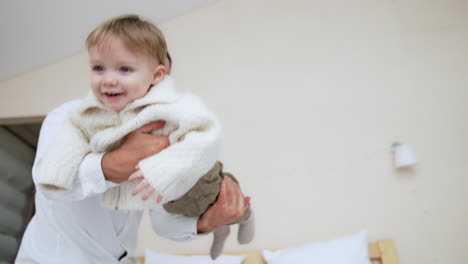 caucasian father waves his lovely baby boy. dad plays with his little son at home. low angle view.