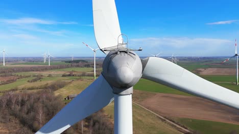 Close-up-shot-of-energy-producing-wind-turbine-in-a-vast-field-on-a-sunny-day-in-Taurage,-Lithuania