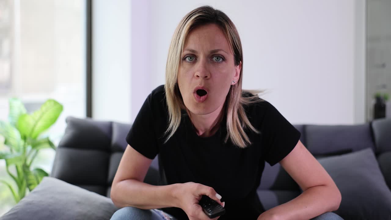 Vrouw zit op de bank en kijkt naar een interessant moment op tv.