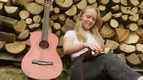 Beautiful-country-girl-guitarist-composes-song-lyrics-rustic-log-scene