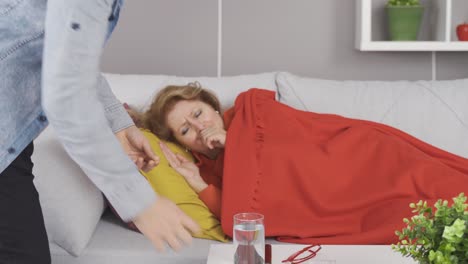 hijo dando medicina a su madre enferma.