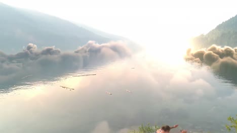 Female-friends-performing-yoga-against-river-and-mountain