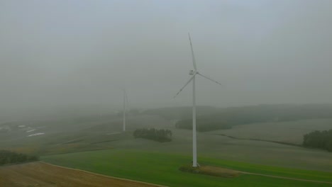 Aerial-footage-close-up-to-wind-farm,-windmill-during-fog,-grey-landscape-around,-renewable-energy-in-the-open-field,-below-natural-landscape,-green-energy-is-important