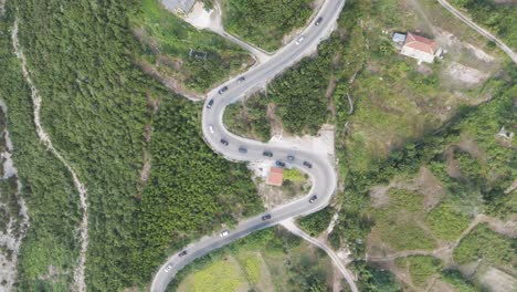 high aerial top down view of cars drive on albanian serpentine road in line