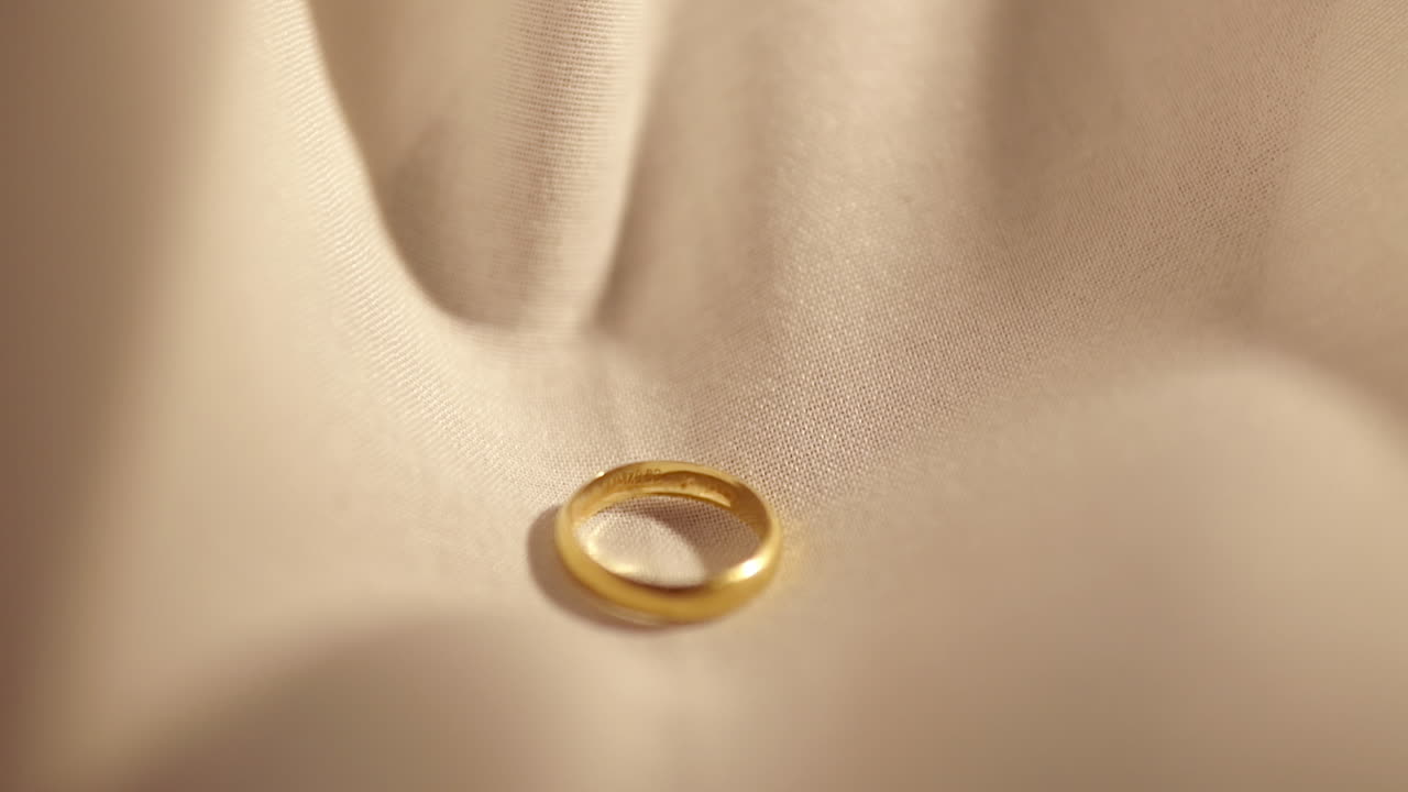 Wedding Gold Rings dropped on white cloth background