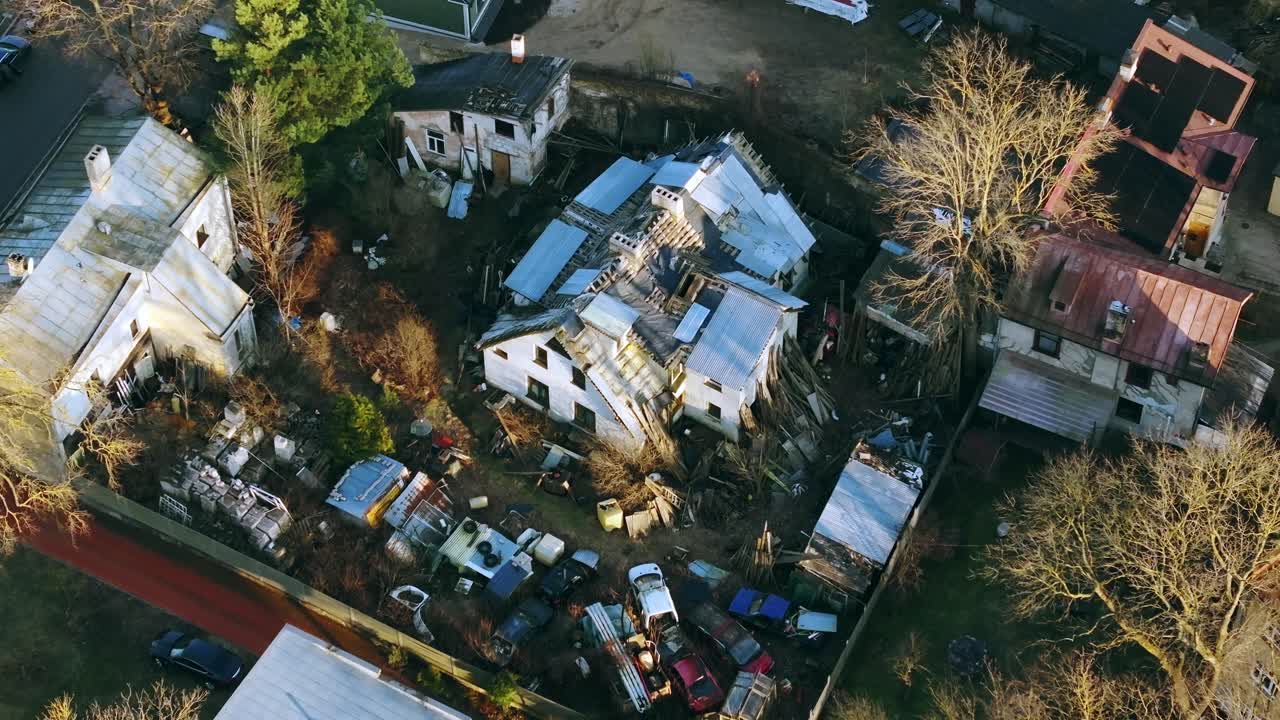 Aerial of junk-filled backyard surrounded by collapsing houses in winter Riga